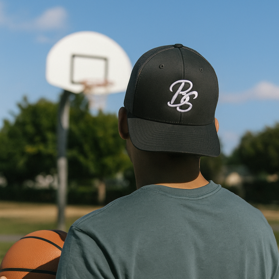 Person wearing a black cap with a Basketball Savant logo on a basketball court